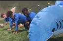 Finny the Shark, the mascot of Peterborough Cathedral's summer exhibition 'Monsters of the Sea', training with Peterborough United Football Club players.